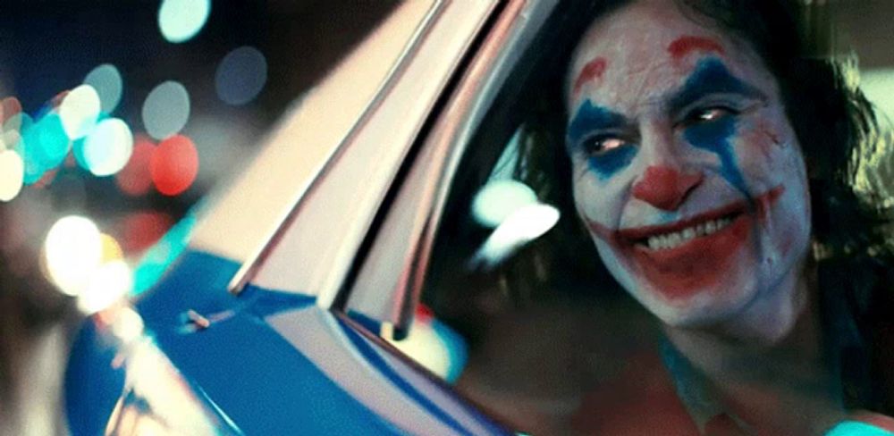 a woman dressed as the joker is sitting in a car and smiling .