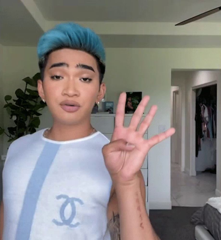 a man with blue hair is wearing a shirt with a chanel logo