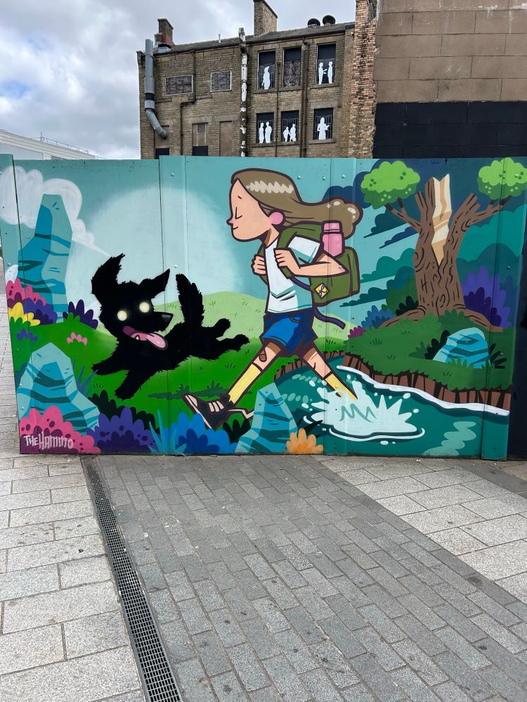 Street art painted on a board covering works going on at Ashton Market in Ashton-Under-Lyne.