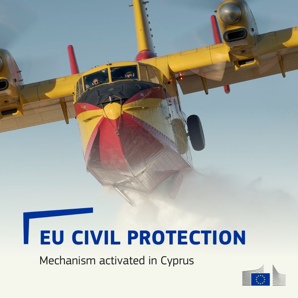 A yellow and red firefighting plane releases water mid-air, seen from a frontal low angle. Text reads: 'EU Civil Protection – Mechanism activated in Cyprus', with the European Commission logo at the bottom right