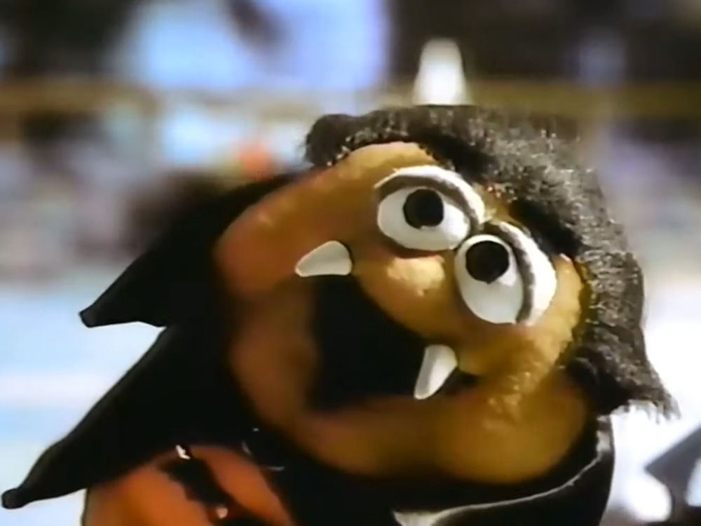 Short version: Puppet McNugget that looks like Dracula... Long version with context: Screen-capture of a scene from a McDonald's television advertisement. Ad featured Halloween-themed chicken nuggets dressed as cartoonish versions of various classic spooky monsters. Shown here is a diagonally standing puppet made to look like a chicken nugget, its spherical eyes in a droopy expression, its mouth open with fangs protruding, implying a vampire. It also wears a cape with a clasp and has slicked-back hair reminiscent of Bela Lugosi's depiction of Dracula. It has no arms or legs (it's a nugget, though with a plush texture as you might see on a Muppet). The nugget creature laughs at a pun made by a Frankenstein-like character earlier in the commercial about having gotten the recipe of the thing they're cooking from their "Mummy". The image is probably not terrifying to most viewers given its cartoony features