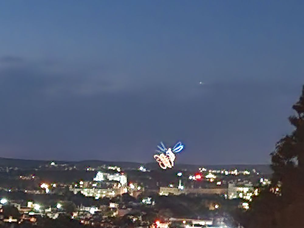 A drone display of a hummingbird at a flower flapping its wings