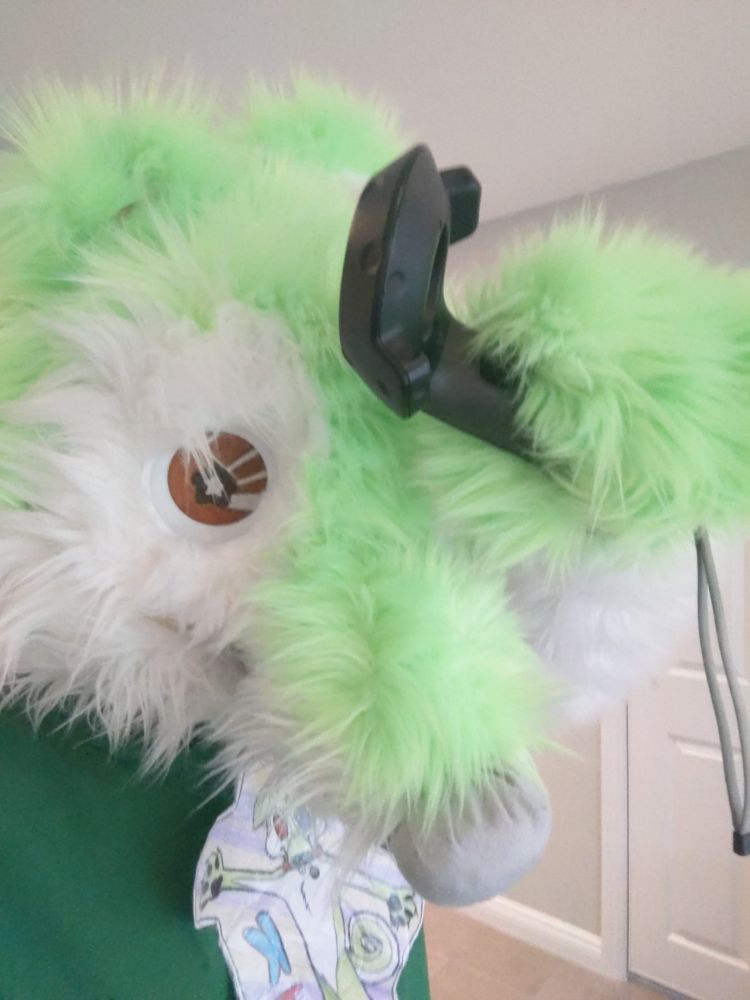 Photo of my Kiwano fursuit head from 2020 featuring an HTC Vive controller being held with a paw.