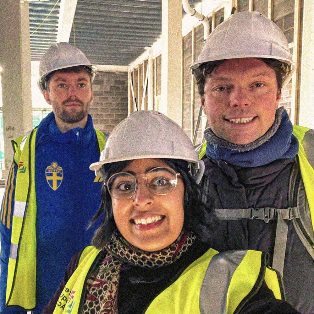 James, Gugan and Lee at the building site wearing high-vis and helmets