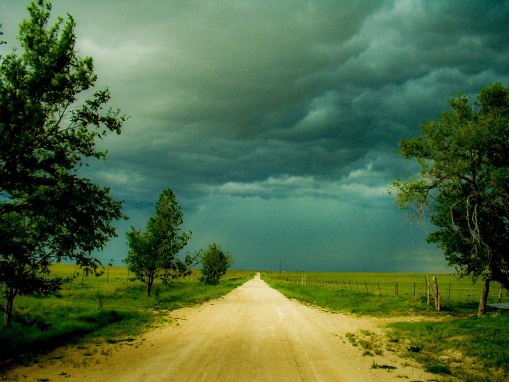 White caliche road under stormy skies and green grass