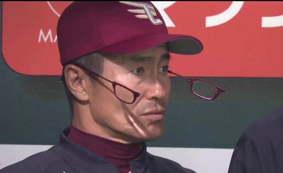 a guy wearing a rakuten golden eagles baseball cap, his glasses are split in the middle as if he were surprised