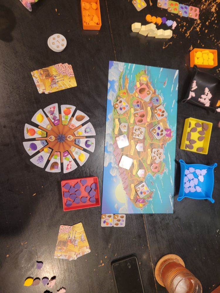 The colorful boardgame Finca laid out on a black table. A windmill next to a map of the island of Mallorca.