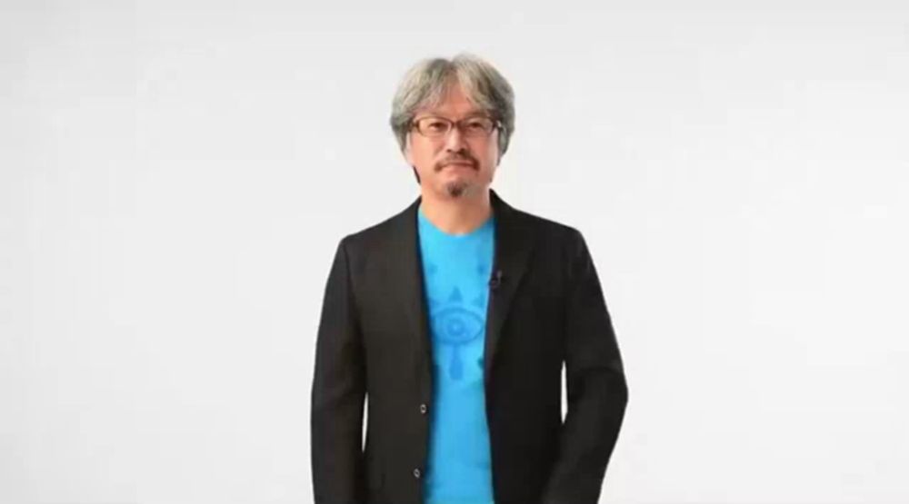 a man in a suit and blue shirt is waving in front of a white background that says hello