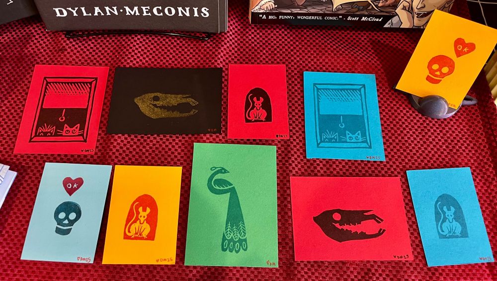 Small linocut prints on colorful cardstock in different colors of ink.