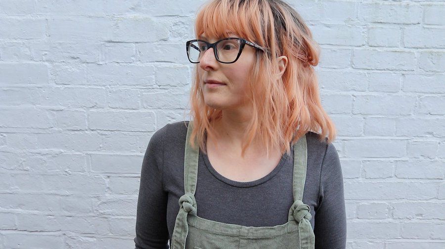 Jen, a thirtysomething white woman, wearing dungarees, glasses and a peach wig 