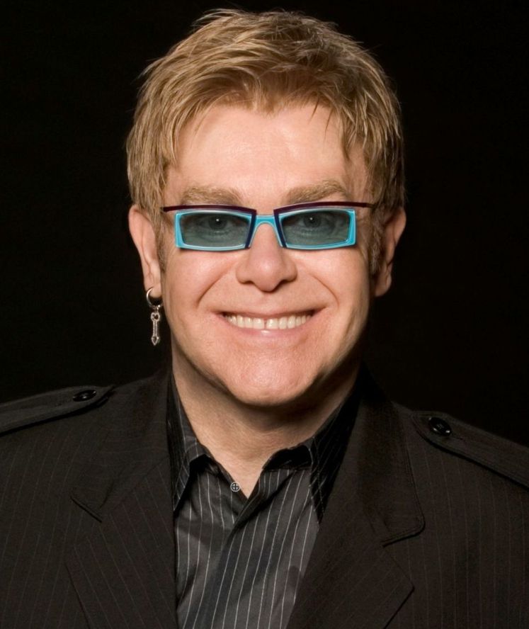 older white guy smiling short blonde hair blue frame shades with square lenses one silver arrow earring black jacket black and white pin stripe shirt black background. hot.

"We live in an age, in an era where there is so much negativity, there is so much violence in the world, there is so much unrest and people are at war, that I wanted to promote the word love and red signifies love."