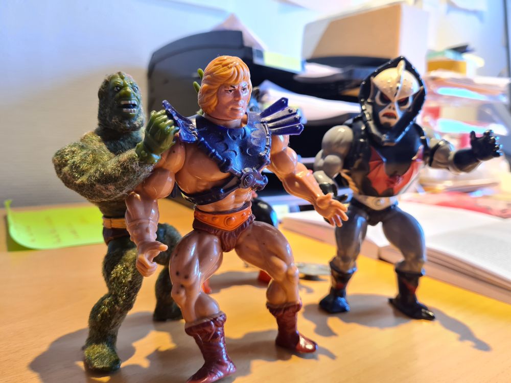 He-Man figures standing on an office desk.