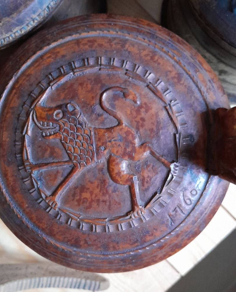 The lid of a wooden cup, carved with what is (probably) supposed to be a lion, but with such skinny legs it looks kind of monkey-like. The mouth is full of teeth and a long happy toungue.