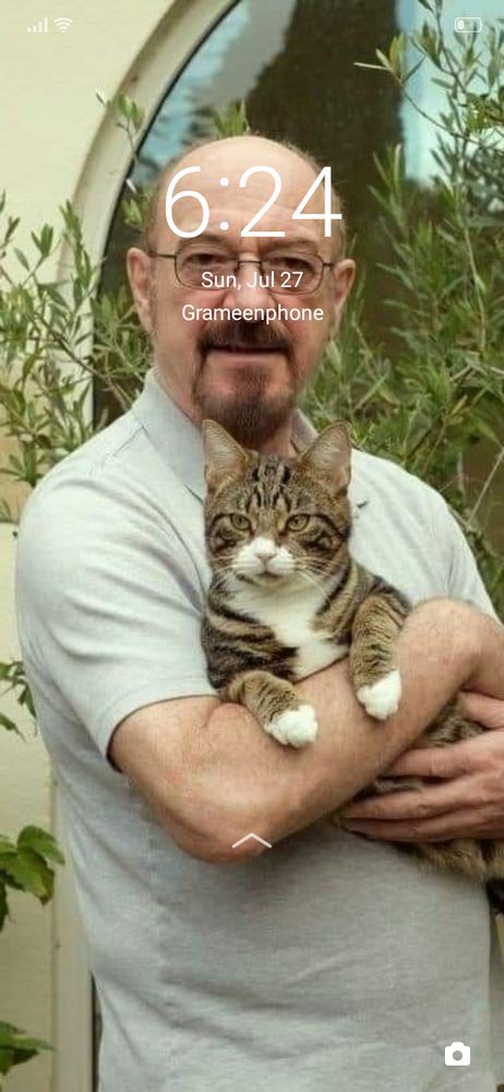 screenshot of a phone lock screen showing Ian Anderson holding a cat