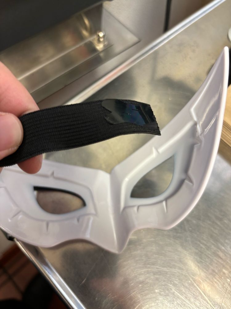 A Persona 5 Joker mask with the elastic band that keeps it on your head broken off on one end