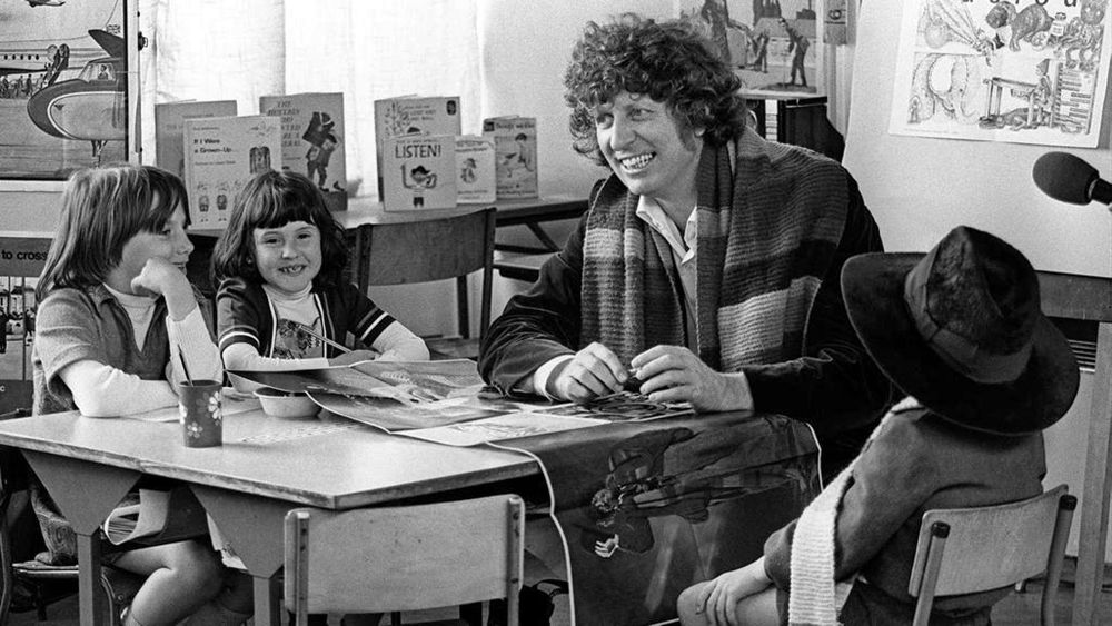 Tom Baker visiting children in Belfast in 1978. He's plonked his hat on one small child's head, and two others are just watching him and *smiling*. They're meeting Doctor Who. Of course they are.