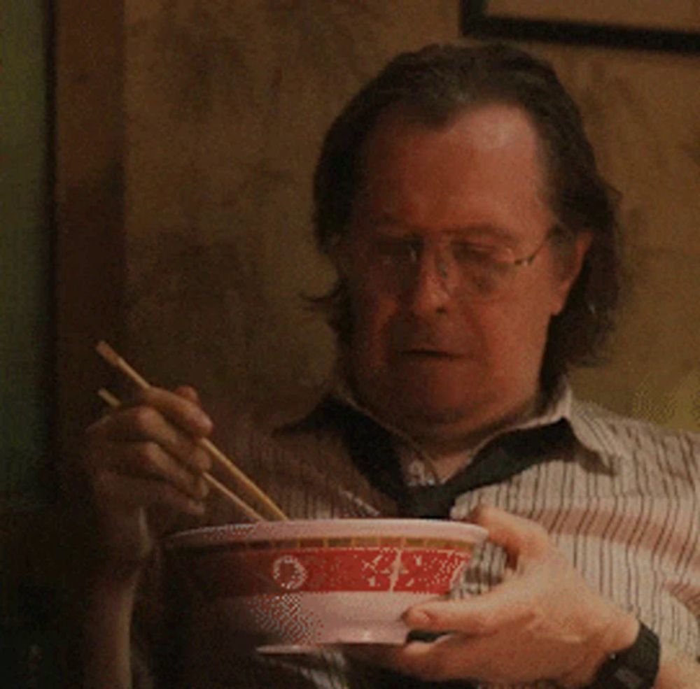 a man eating a bowl of food with chopsticks