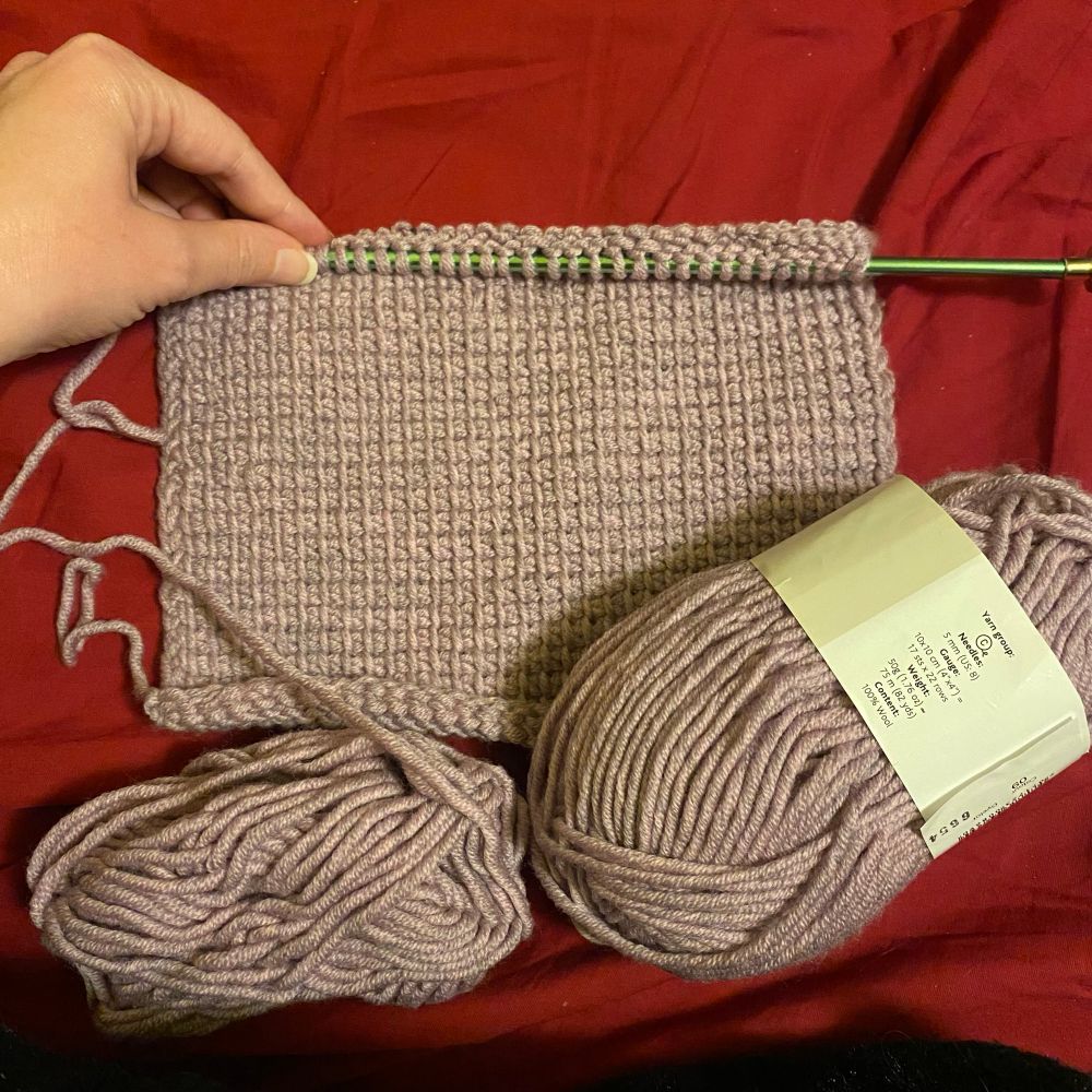 Tunisian crochet rolled out to show simple stitch technique. Yarn currently being used on the bottom left, unused yarn on bottom right. Used yarn considerably smaller. 