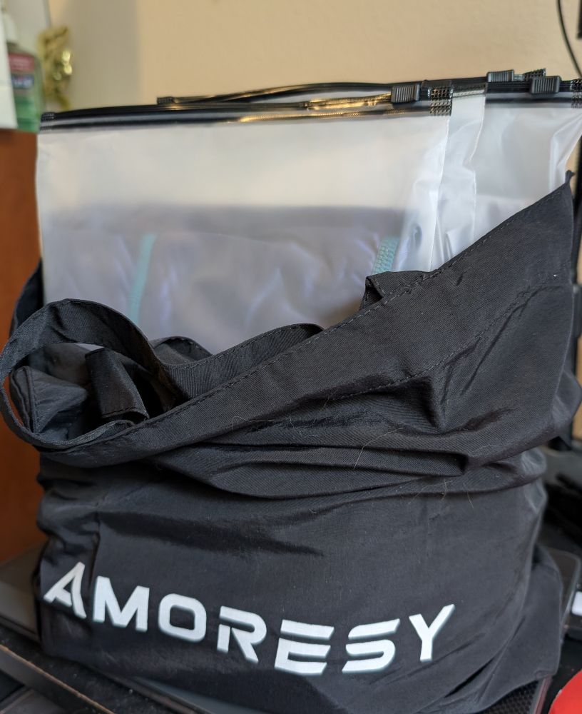 Black bag with the word "Amoresy" on it stuffed with packages of new Amoresy gear
