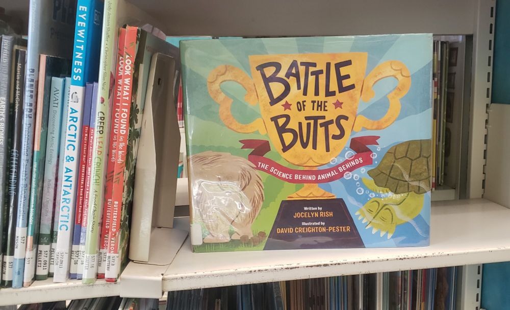Picture of book BATTLE OF THE BUTTS on a library shelf with other books.
