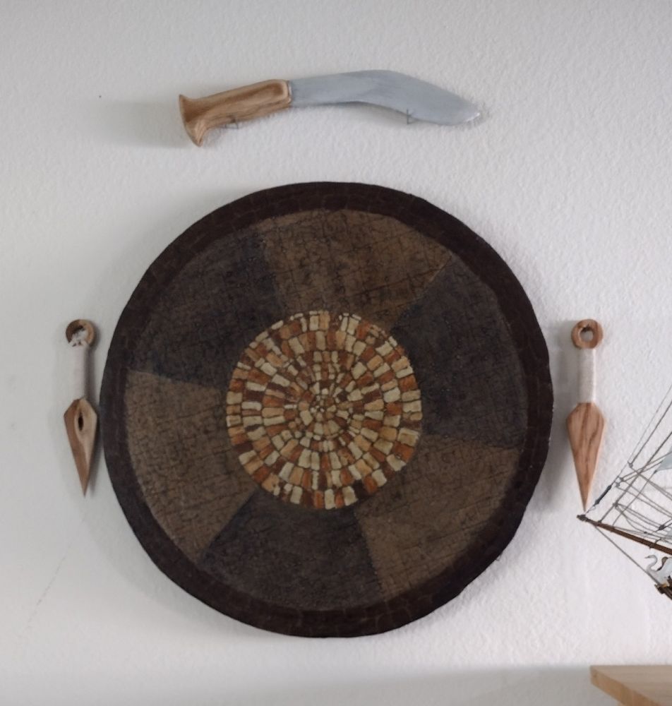 A 21" diameter piece of Ultimate Dungeon Terrain hanging on a living room wall. Ultimate Dungeon Terrain is circular foam painted in different zones for zonal combat in Dungeons and Dragons. This particular piece is painted flagstones of different colors of brown and beige.