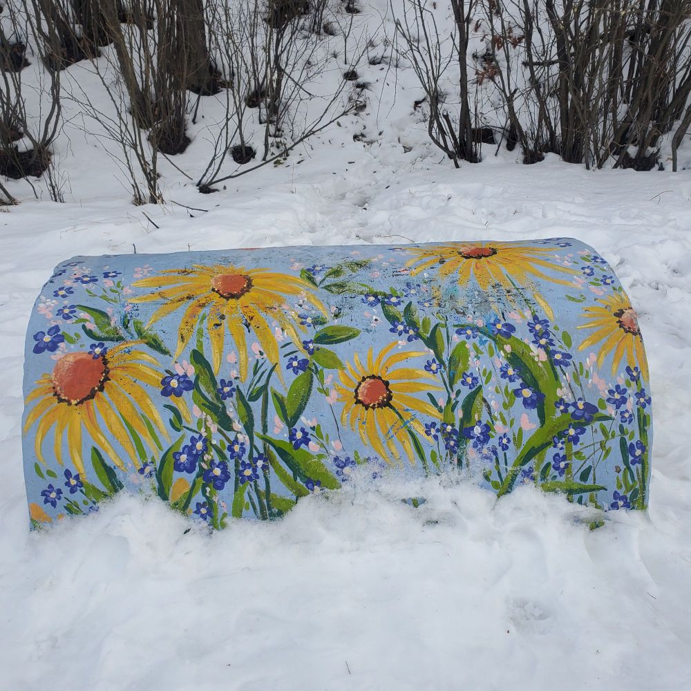 A snowy spot in Edmonton by The End of the World lookout over the North Saskatchewan River. A cement bench is painted with vivid yellow and blue flowers. An inspiring glimpse or reminder of summer in the midst of snowy winter beauty!
