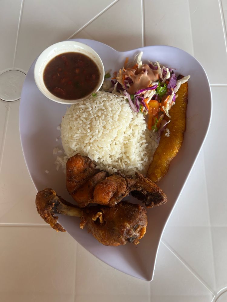 Fried chicken, rice, beans, salad, and plantain on heart shaped plate. 