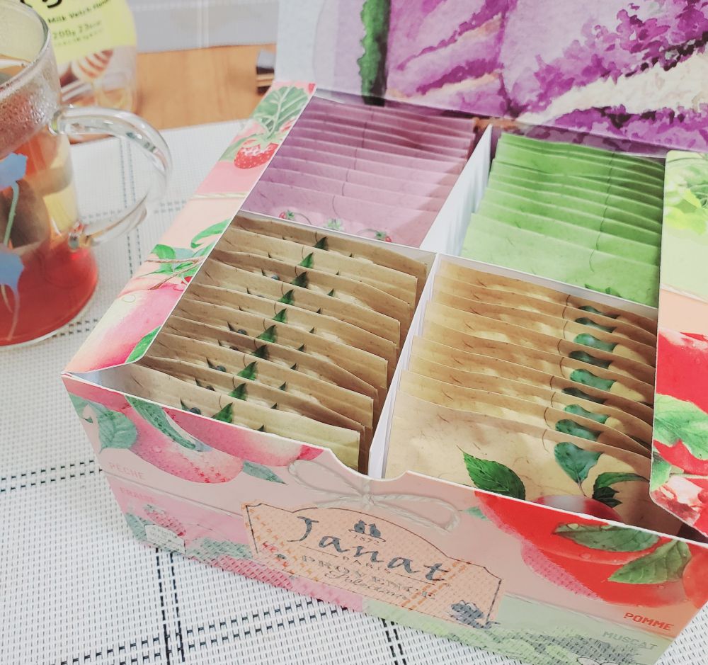 Janat 4種のフルーツフレーバーティー
花や果物が描かれたパッケージ、背景のガラスカップ