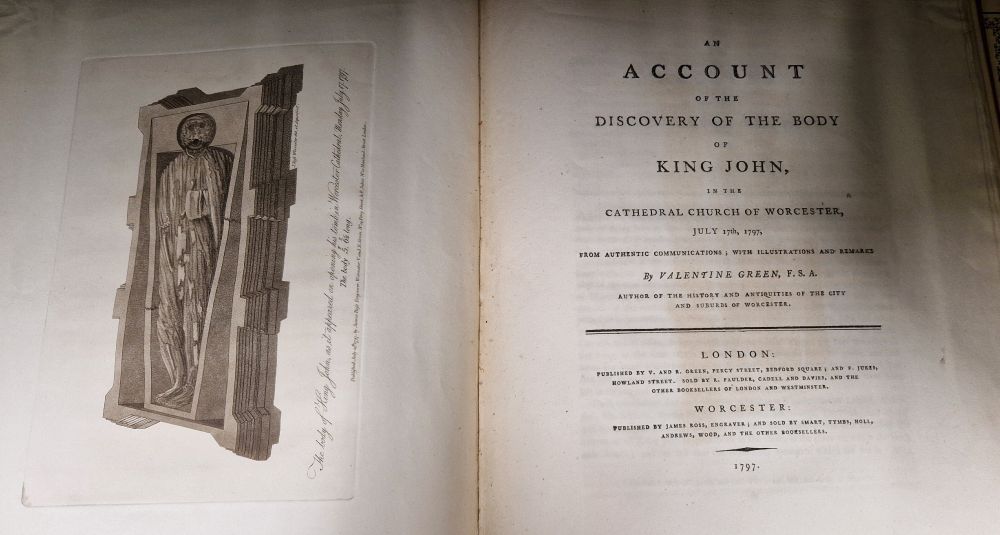 Old pages of book. Left page is an illustration of a body in a tomb. Right page is title page. 