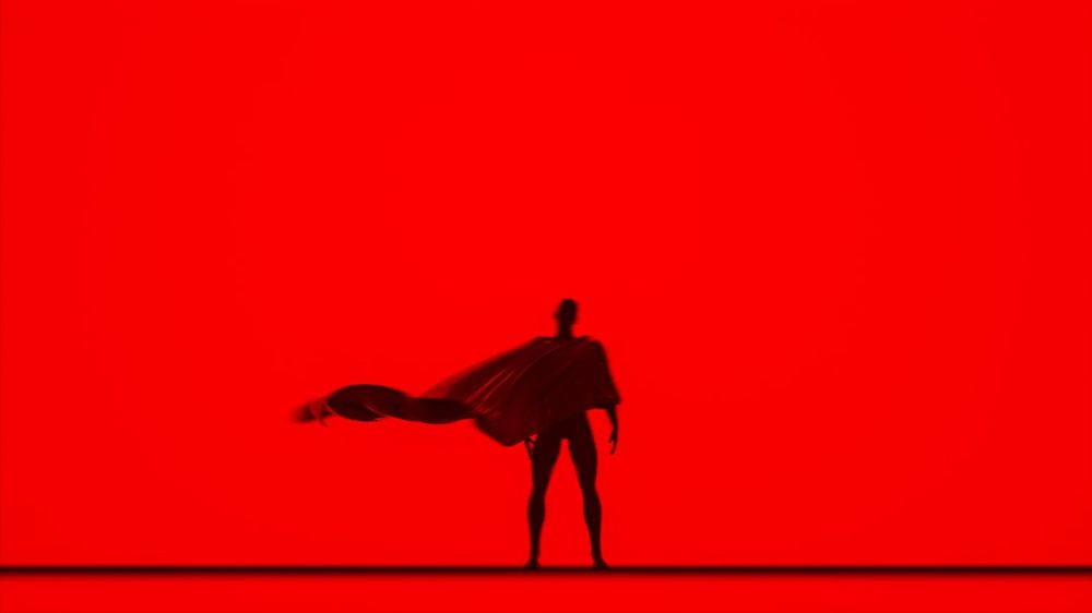 A cartoon image of Superman silhouetted against a vibrant block red background. 
