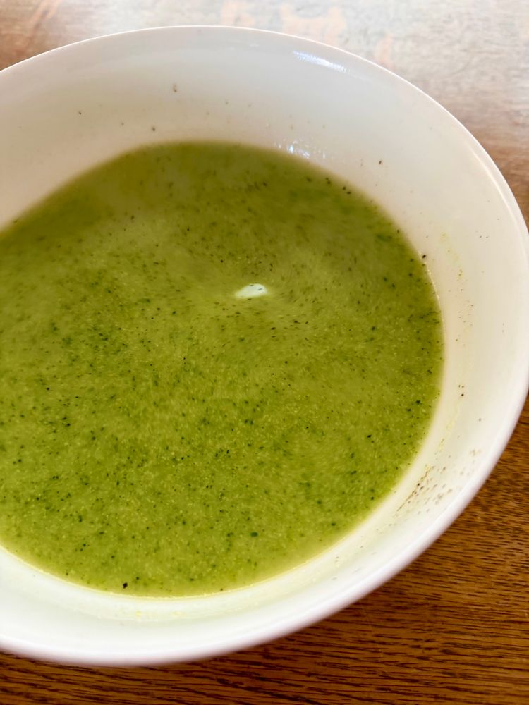 Eine pürierte Brokkoli Suppe in einer weißen Schüssel auf einem Holztisch 