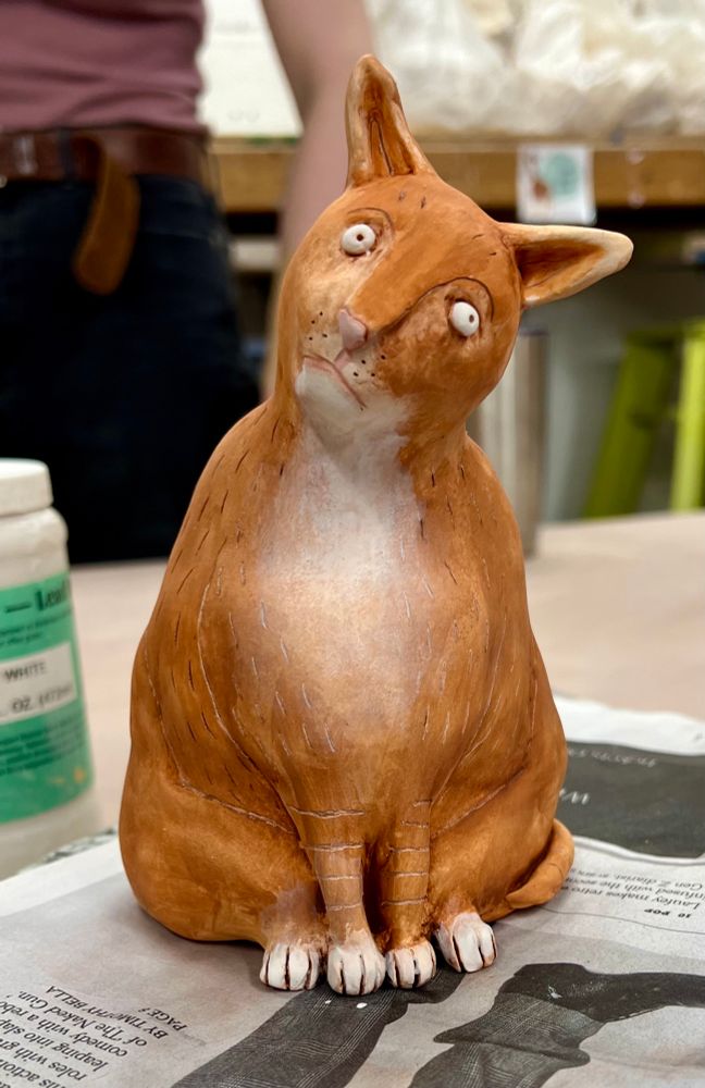 It’s a ceramic orange and white cat meant to look like those weird medieval cats but without any of the fun poses or props because I’m not skilled enough to pull that shit off. He sits with his head tilted and stares into the distance uncertainly with bulbous human eyes.