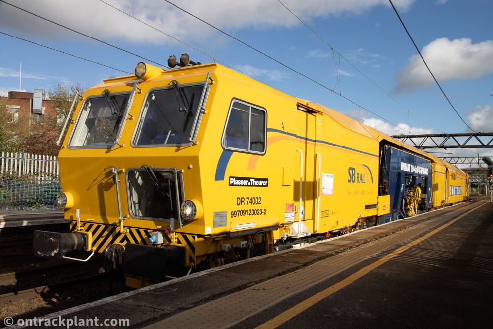 a large yellow railway machine stands in a platform under a glorious blue sky