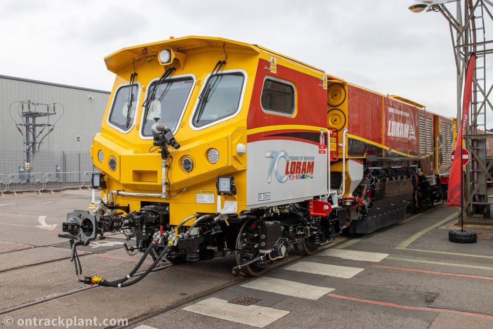 a red, white and yellow railway grinding machine