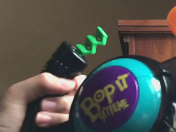 Close up of a hand holding a bop it game near the “flick it” lever