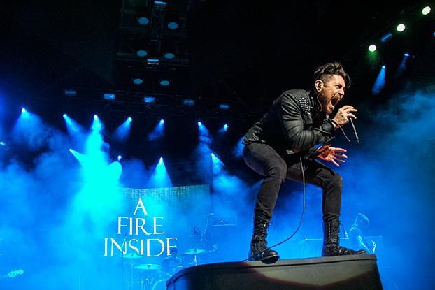 Davey Havok standing atop a speaker, back arched and knees bent as he belts out an emotional tone with AFI.