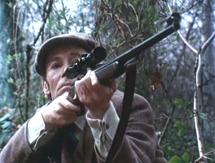 An English gentleman, in about 1939, in woodland, raising a long-range rifle to his shoulder. This may be a scene from a film, starring Peter O'Toole, or it may not be.