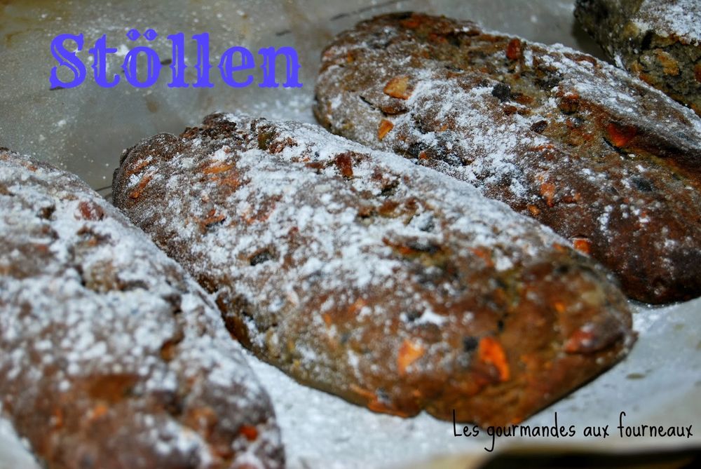 Several loaves of German “stöllen” bread with dried fruit, baked and laid out, with powdered sugar sprinkled on top. There is a text label “Stöllen” in blue on the upper left. 