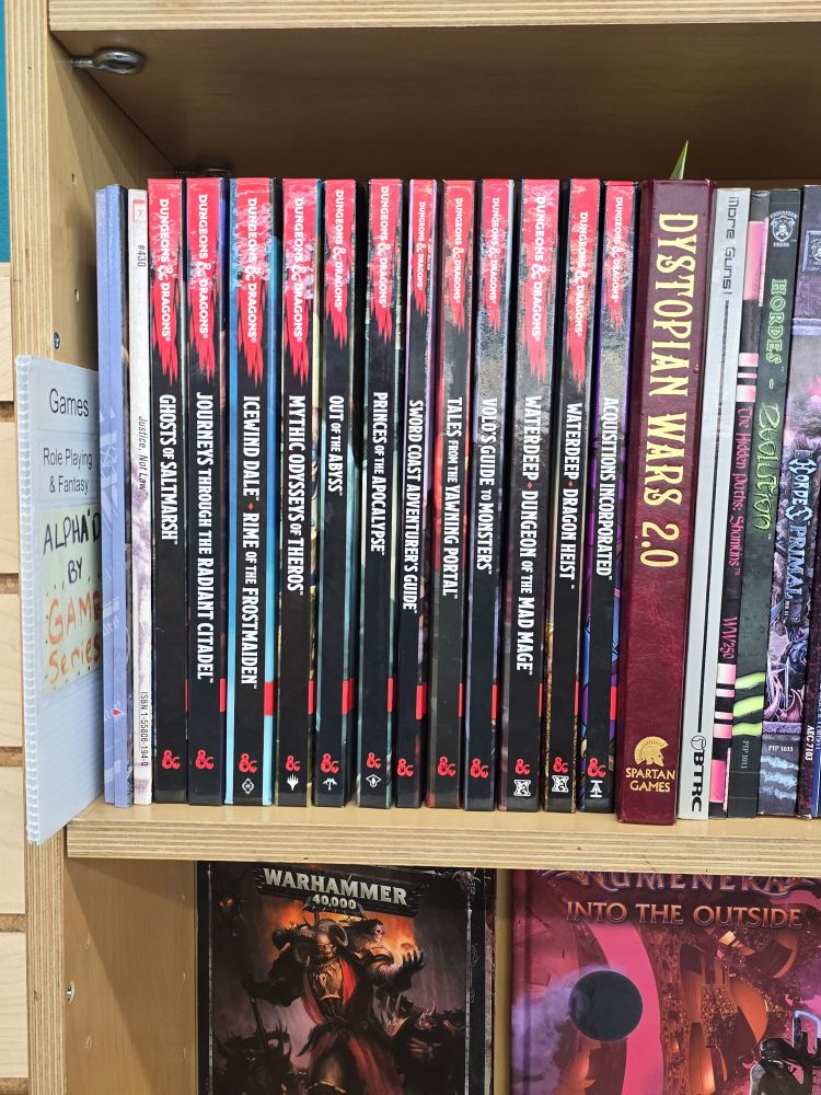 Shelf of various 5e D&D books.