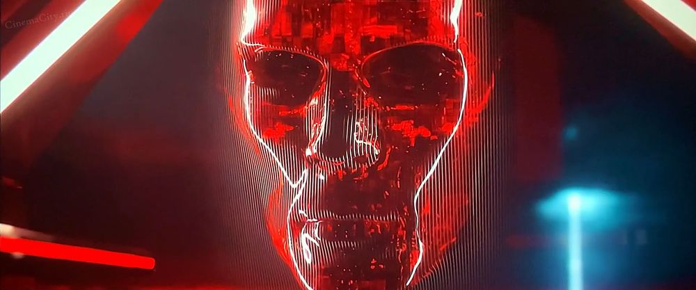 the giant red face that julian dillinger uses to interface with ares in tron ares, who genuinely looks more like a modern take on the mcp from tron 1982