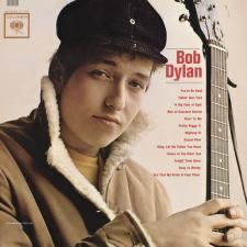 Bob Dylan album cover. A young man in a coat and hat with a guitar 