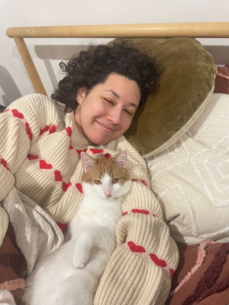 Girl with curly hair cuddling a cat in bed
