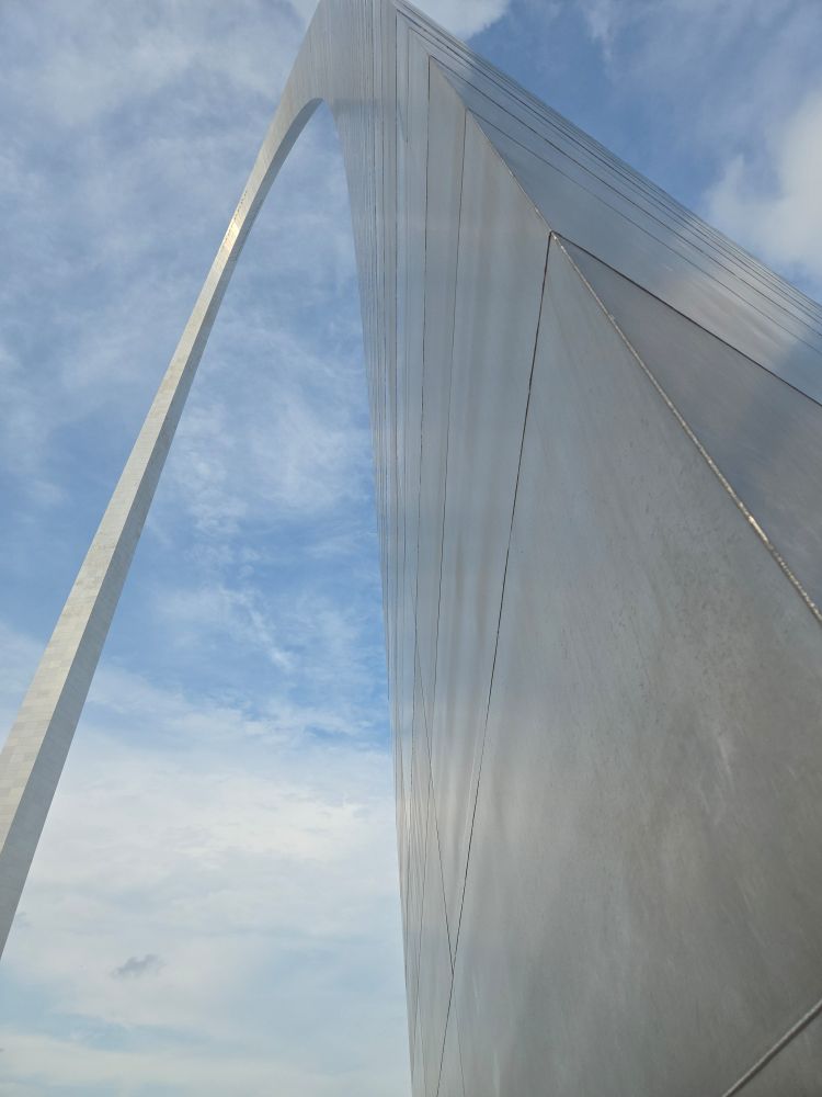 The Gateway Arch as seen from the bottom of one side. The sky is blue with a lovely scattering of clouds