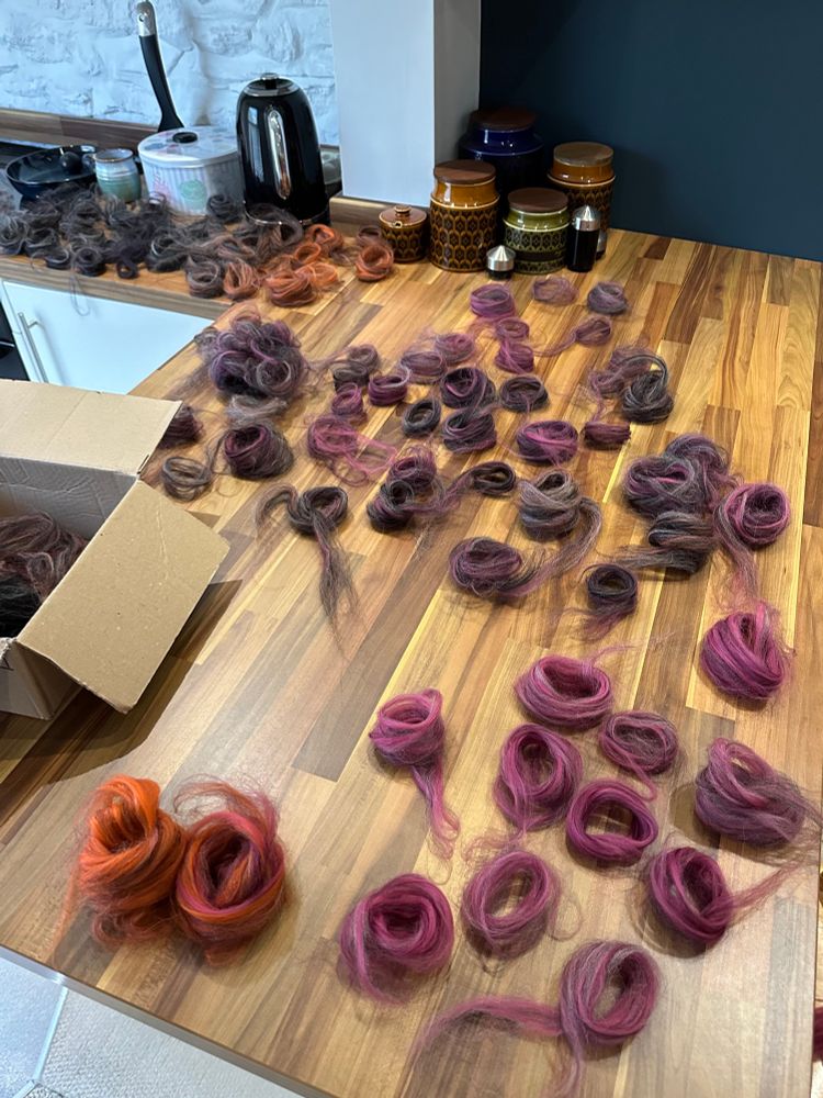 Little nests of spinning fibre in different colours litter a kitchen work surface. 