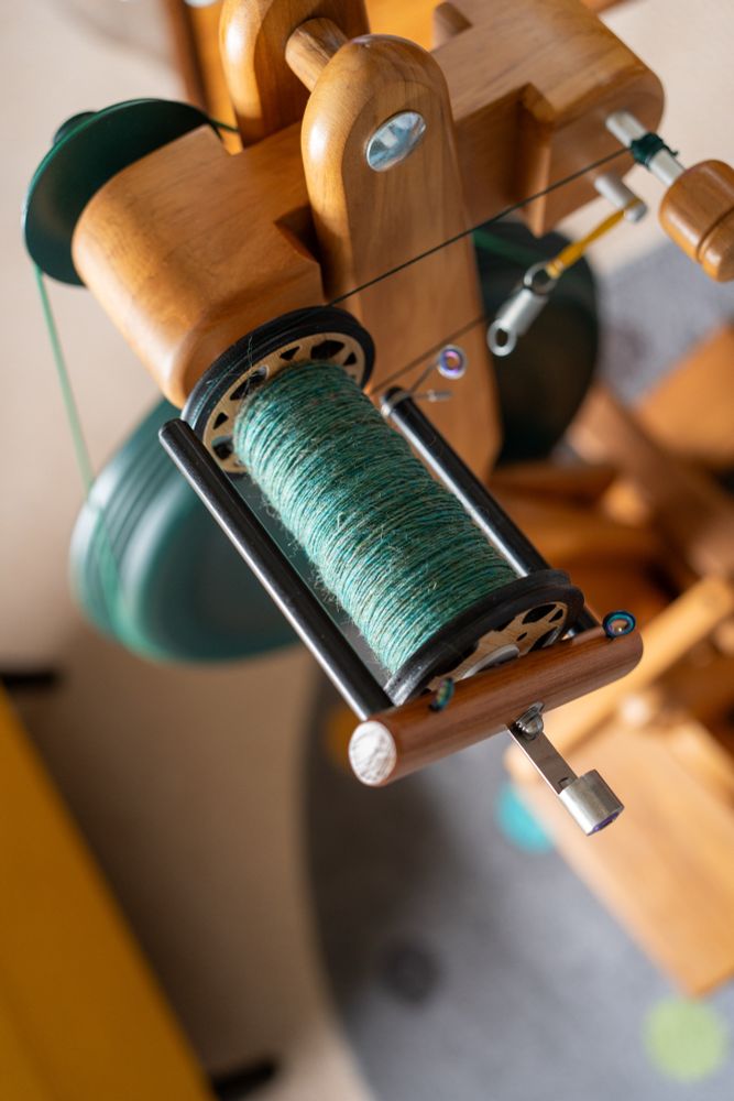A bobbin containing Mineralogy ‘Malachite Magic’ (a mid-teal) on a Majacraft Suzie Pro spinning wheel. 