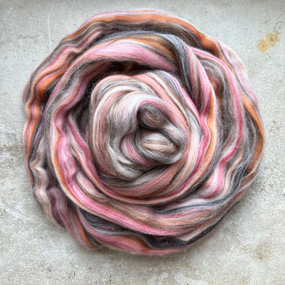 A spiral of blended tops (lengthways colour stripes), containing pink, orange, brown, white and black. 