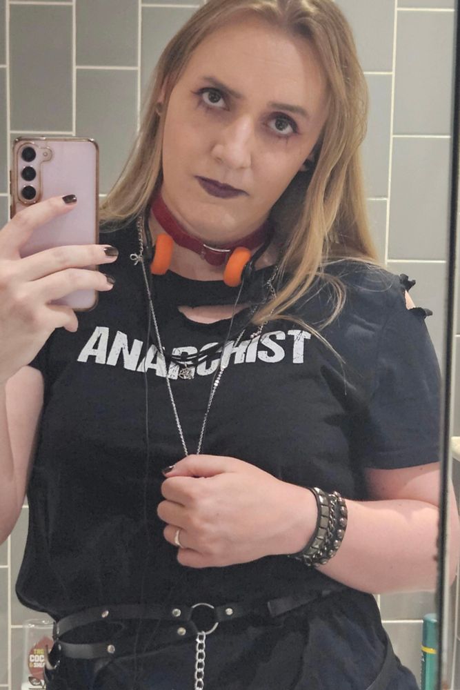 Unwilling Delta Green agent wearing a tattered 'Anarchist' t-shirt and various belts and accessories not suitable for field work.