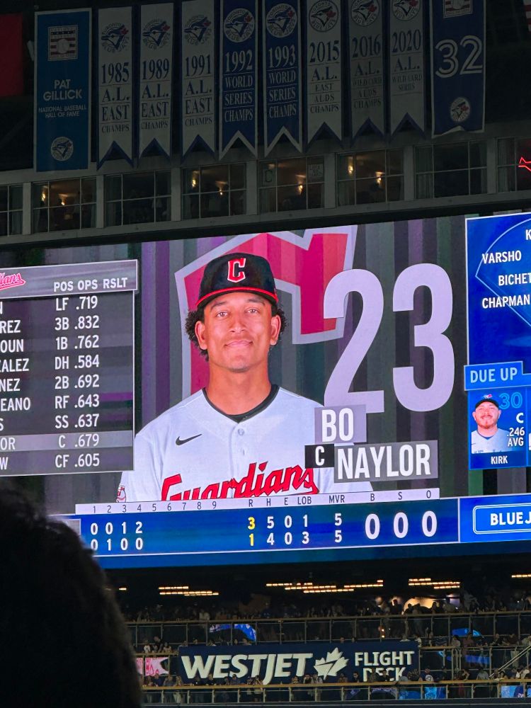 Photograph of a jumbo screen at a baseball stadium displaying the picture and name of the baseball player Bo Naylor