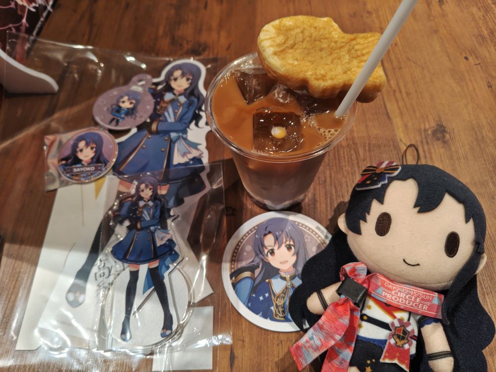 アイドルマスターミリオンライブ　STARDOM ROAD THEATER コラボカフェにて、劇中で「笹森藍」役を演じた高山紗代子ちゃんのミニパネル・アクリルスタンド・缶バッジ・ストロータグ・コースターと、コラボメニューの和風たい焼きカフェラテ。その隣には紗代子のぬいぐるみが置かれている。