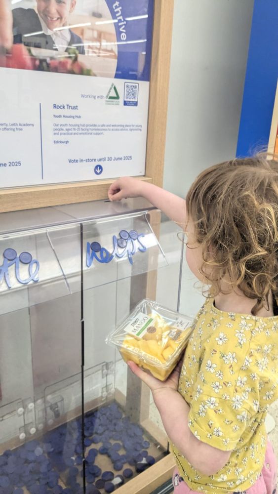A toddler at a Tesco store in Edinburgh inserting a token in the box to vote for Rock Trust.